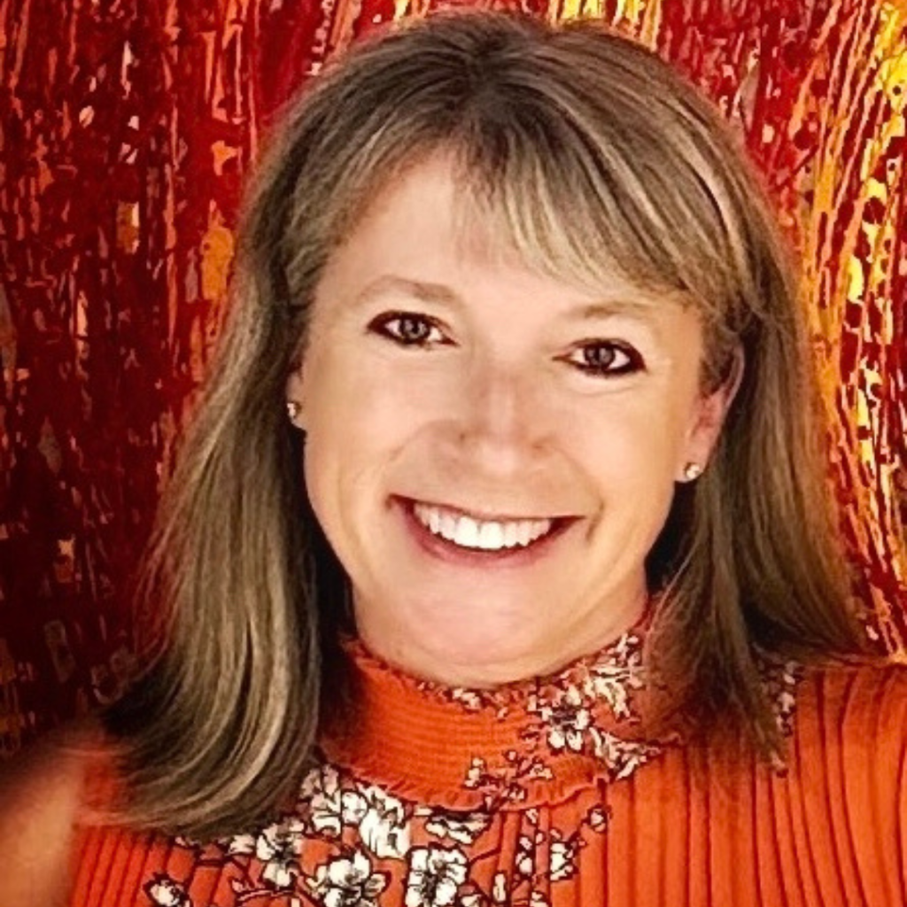 Jodi Morris in front of a red background wearing a red dress